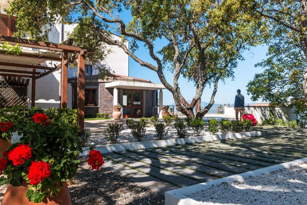 a garden in front of a house with red flowers at Hotel Il Querceto in Dorgali