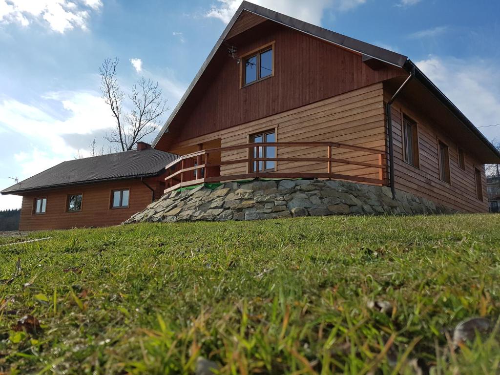 a large wooden house on top of a green field at Agroturystyka Pawlikówka in Lipinki