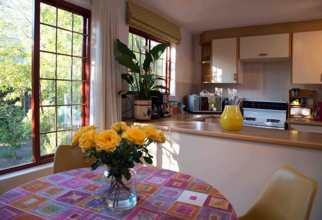 a vase of yellow flowers on a table in a kitchen at Meadows Mountain View in Hout Bay