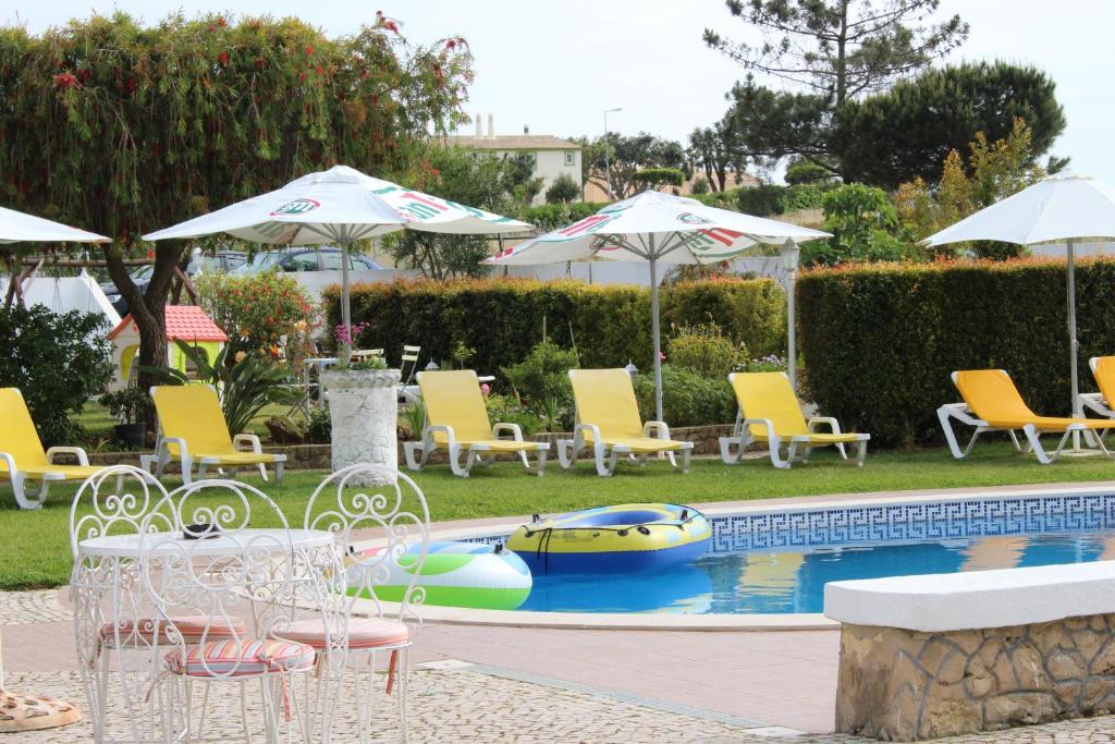 a pool with chairs and umbrellas and a boat in it at Sunshine in Albufeira