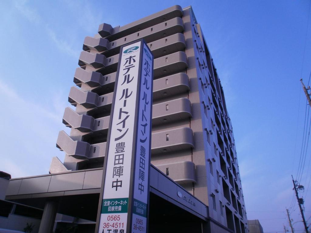 a tall building with a sign in front of it at Hotel Route-Inn Toyotajinnaka in Toyota