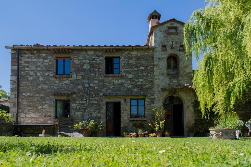 an old stone house with a tree in front of it at Agriturismo Montecorboli in Barberino di Val dʼElsa