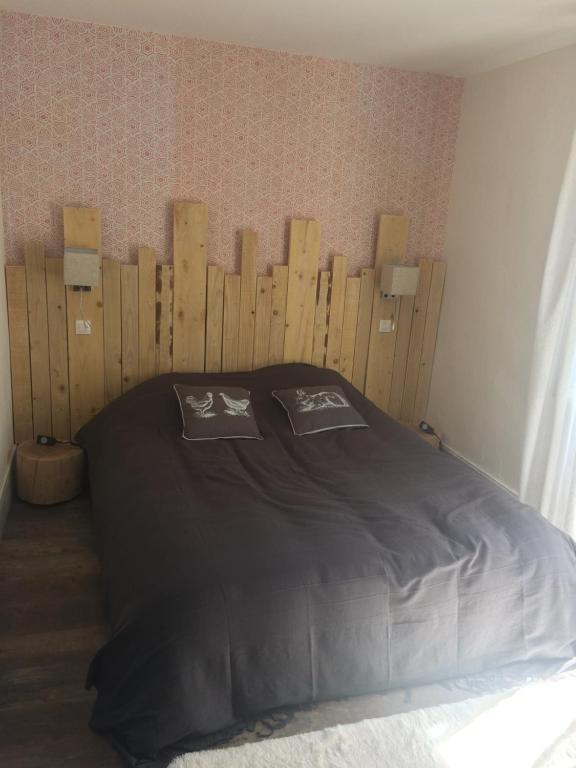 a bedroom with a bed with a wooden headboard at L'ANNEXE in Carennac