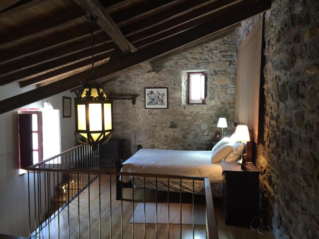 a bedroom with a bed and a stone wall at Charming House Óbidos in Óbidos