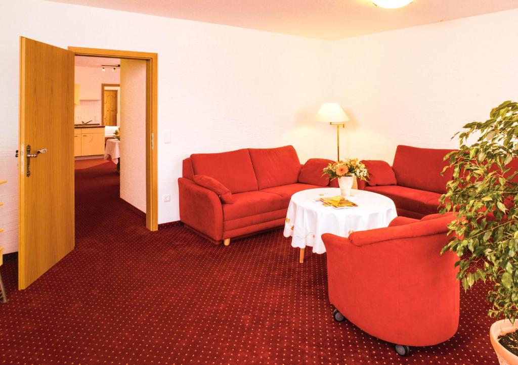 a hotel room with two red couches and a table at Ferienwohnungen Kurhotel Eichinger in Bad Wörishofen