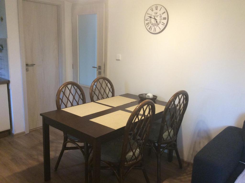 a dining room table with chairs and a clock on the wall at Apartment Garden in České Budějovice