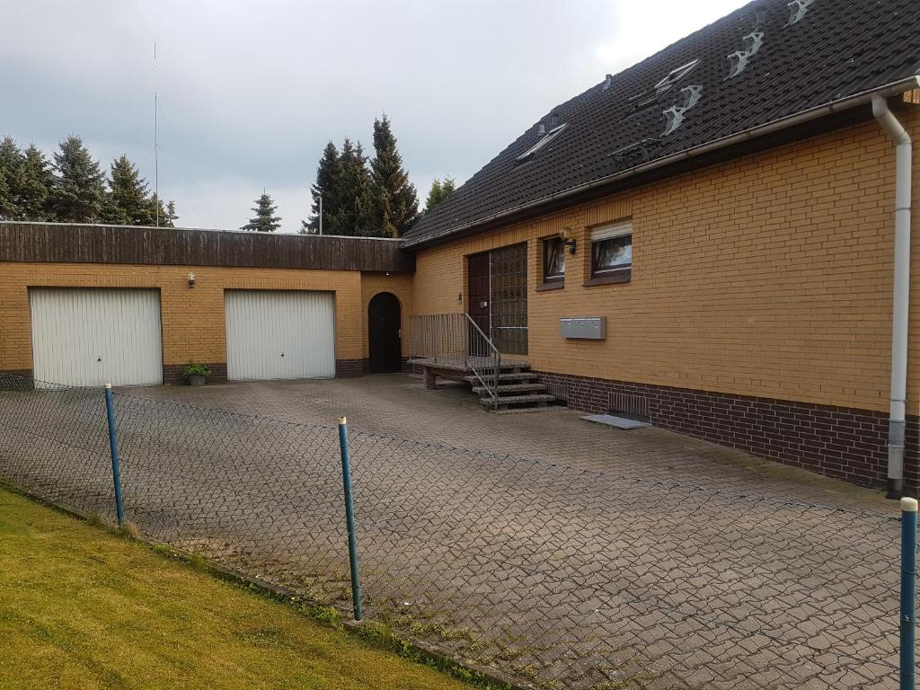 ein Gebäude mit zwei Garagentüren und einem Zaun in der Unterkunft Ferienwohnung Hilker in Hessisch Oldendorf