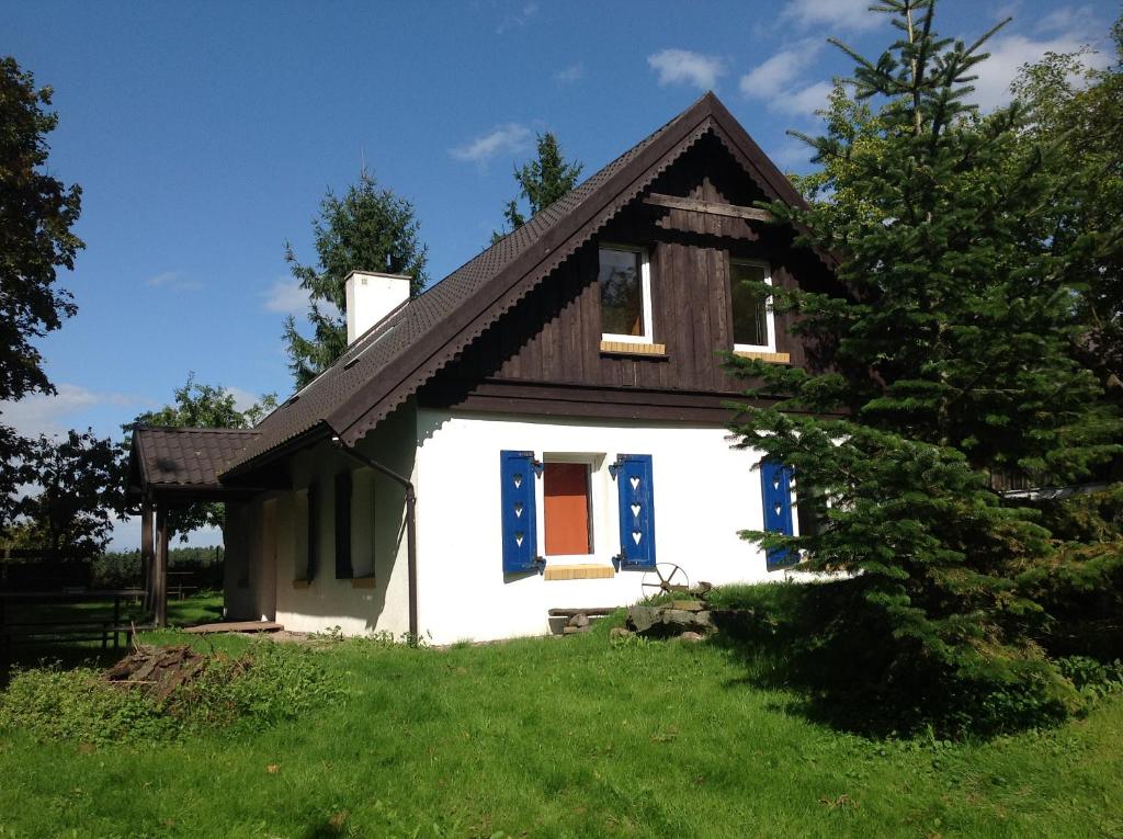 a small white house with a brown roof at Muzyczna Zagroda in Pietzonken