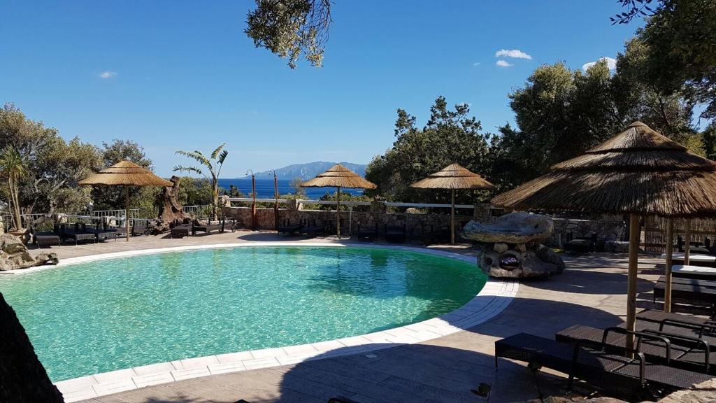 ein großer Pool mit Sonnenschirmen und Stühlen in der Unterkunft I Ginepri Hotel in Cala Gonone