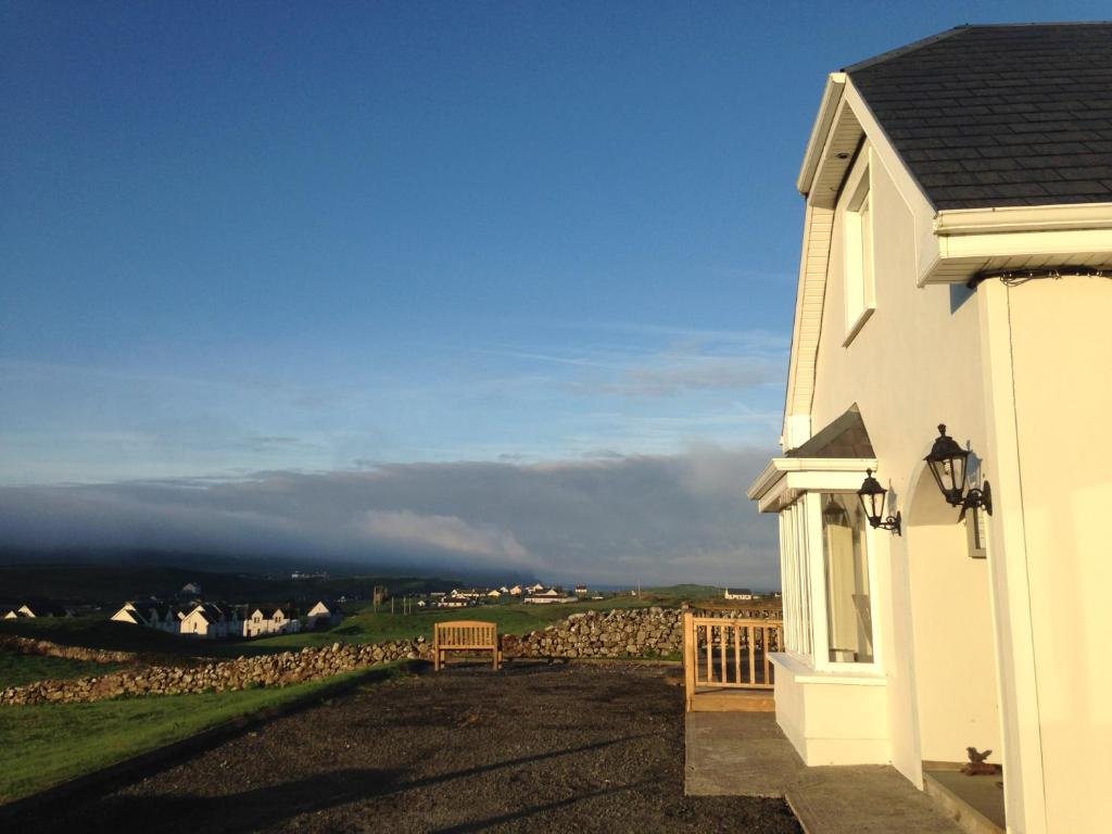 a white house with a bench on the side of it at Doolin View B&B in Doolin