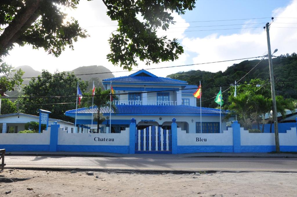 a blue building with flags in front of it at Le Chateau Bleu in Mahe