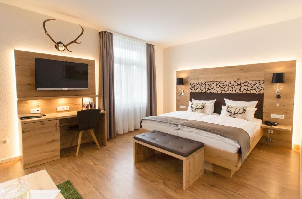 a bedroom with a bed and a desk and a television at Das Waldhotel - Genuss & Wellness am Notschreipass in Todtnau