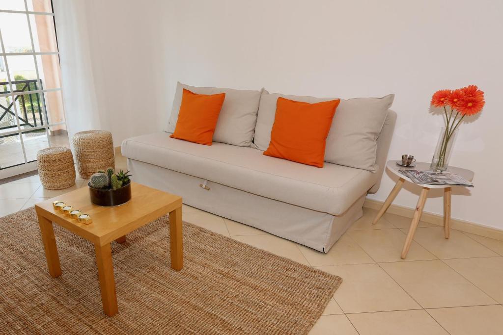 ein Wohnzimmer mit einer Couch mit orangefarbenen Kissen darauf in der Unterkunft Da Ponte Flats - Armacao De Pera Orange Apt in Armação de Pêra
