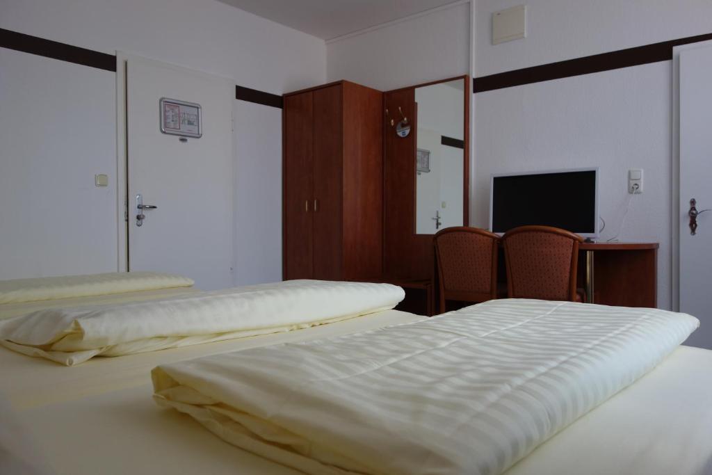 a room with two beds and a television in it at Parkhotel Friedrichstrasse in Gießen