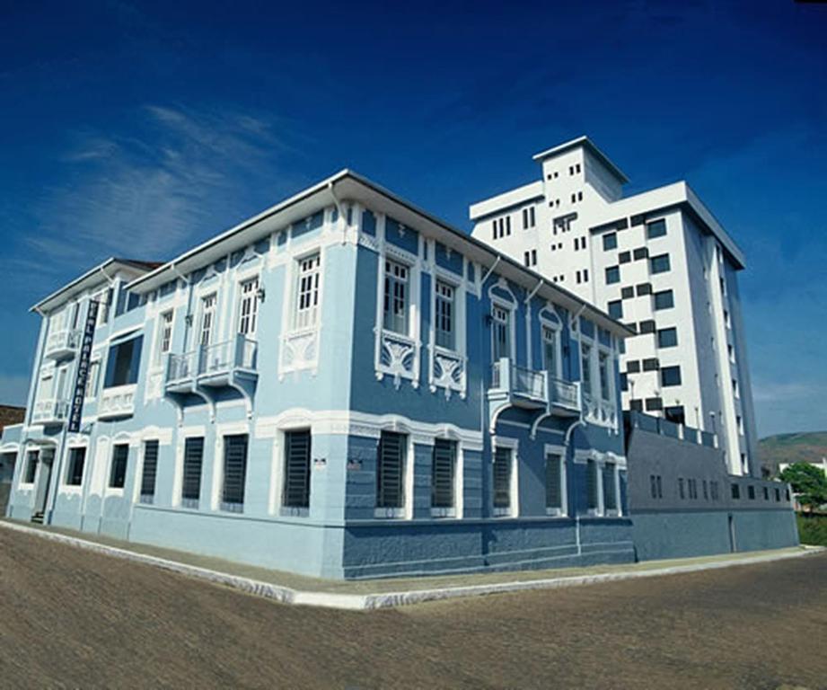 a blue and white building next to a tall building at Real Palace Hotel in Santa Rita do Sapucaí