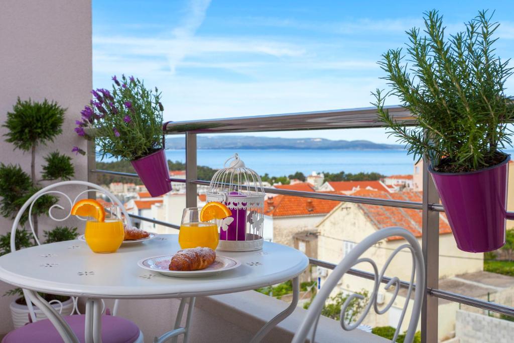 a table with food and orange juice on a balcony at Apartment Ivona in Makarska