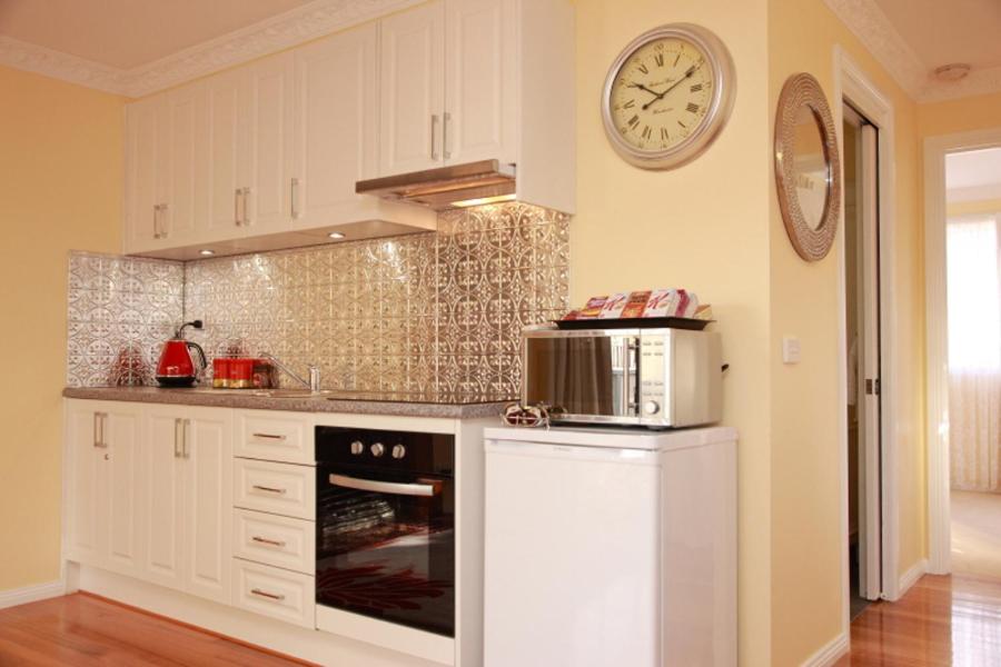 a kitchen with a microwave and a clock on the wall at Secret Cottage in Healesville