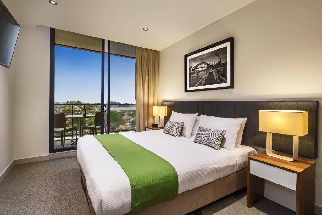 a bedroom with a large bed and a large window at Quest Chatswood in Sydney