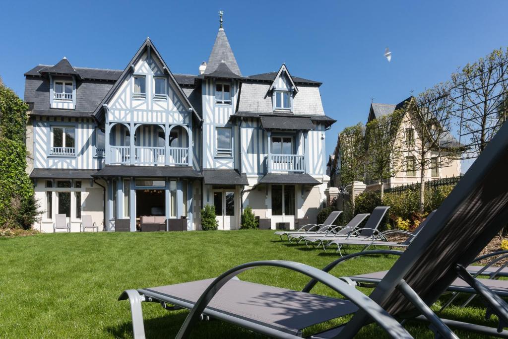 a large house with lawn chairs in front of it at Villa Odette in Deauville