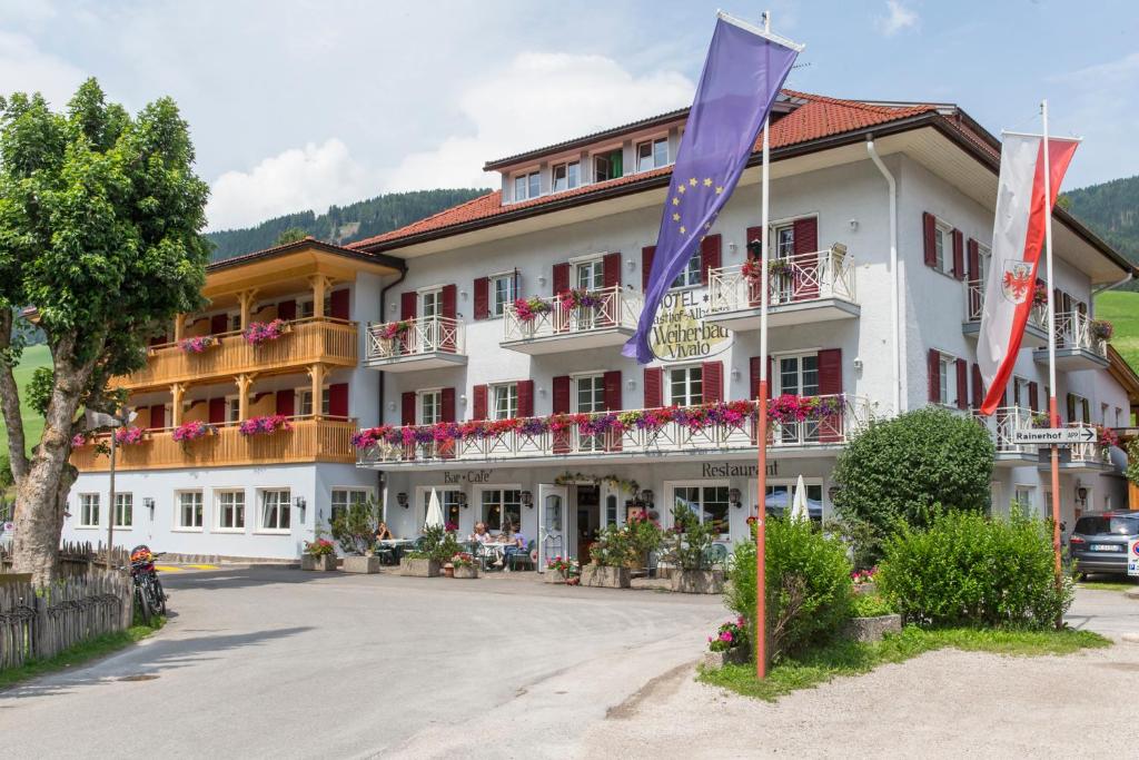 un gran edificio blanco con banderas delante en Hotel Gasthof Weiherbad, en Villabassa