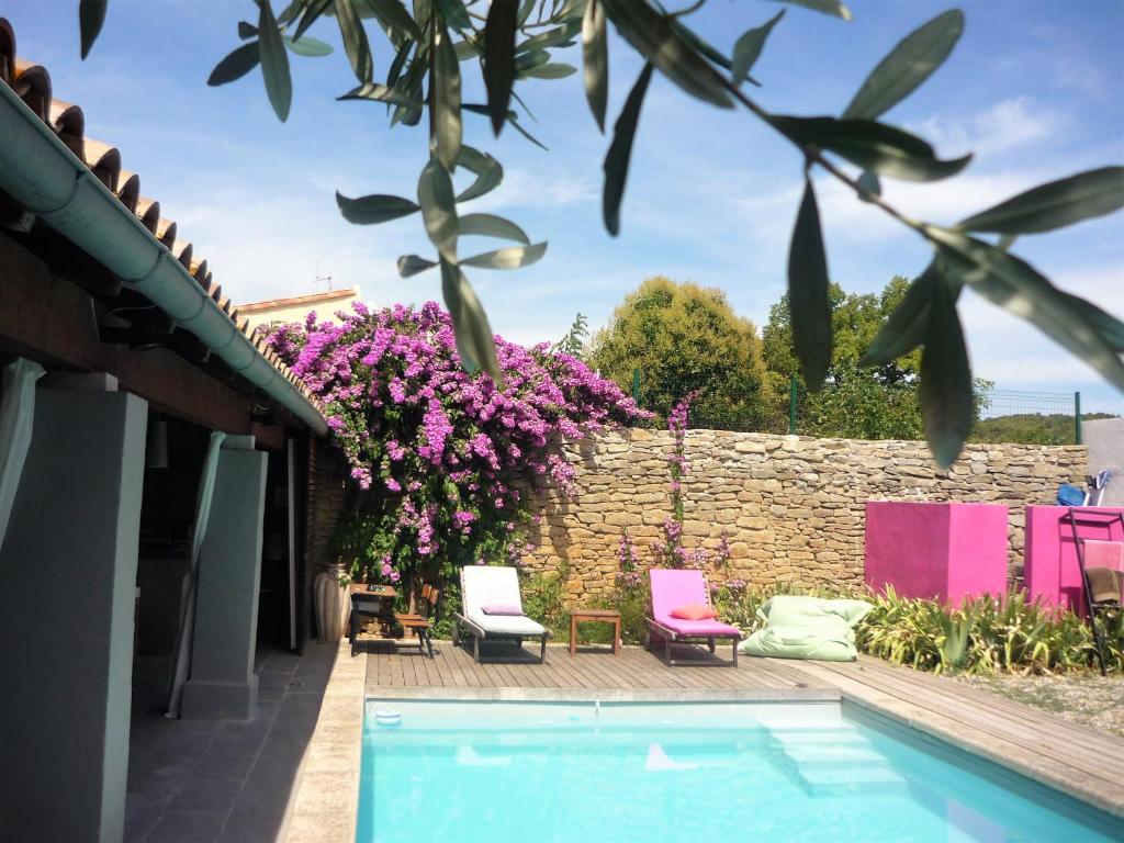 un jardin avec une piscine et des fleurs roses dans l'établissement Chambres d'hôtes La Pierrerie, à Laure-Minervois