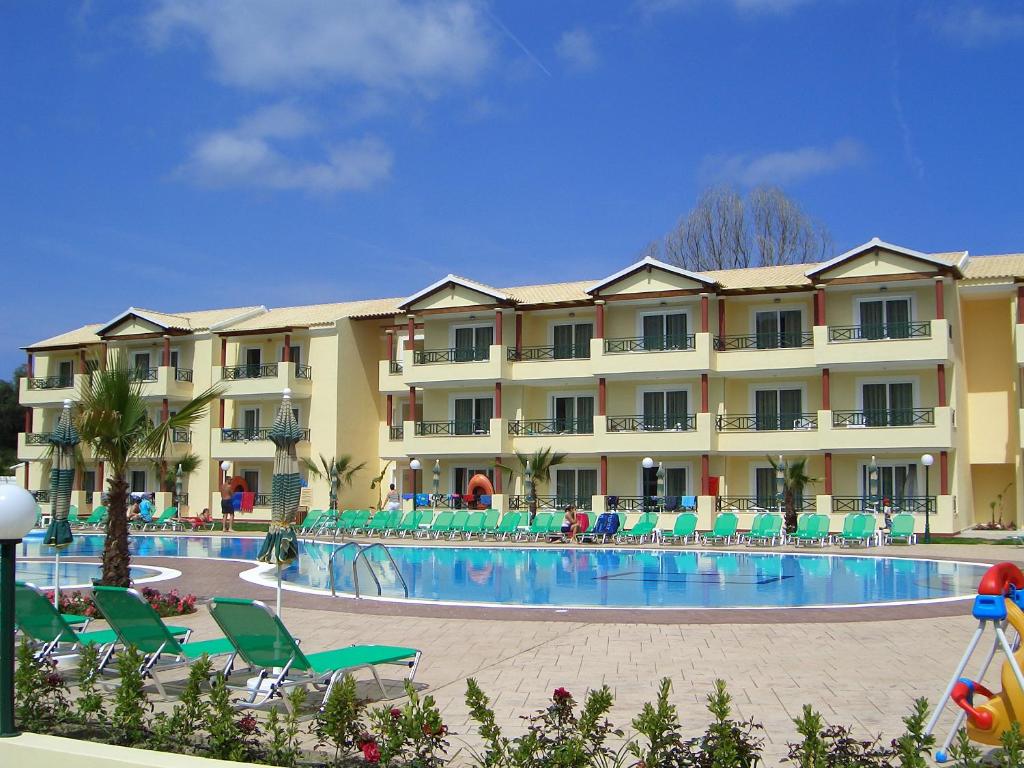 a large hotel with a swimming pool and chairs at DAMIA HOTEL Apts in Sidari