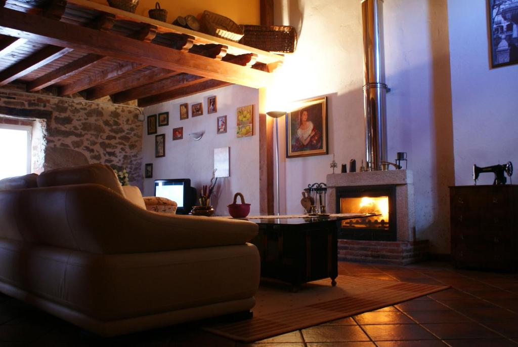 Casa Rural Alto Santiago في Santiago del Collado: غرفة معيشة مع أريكة ومدفأة