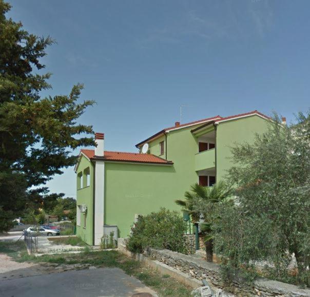 zielony budynek z drzewami przed nim w obiekcie Apartment Beni w Medulinie