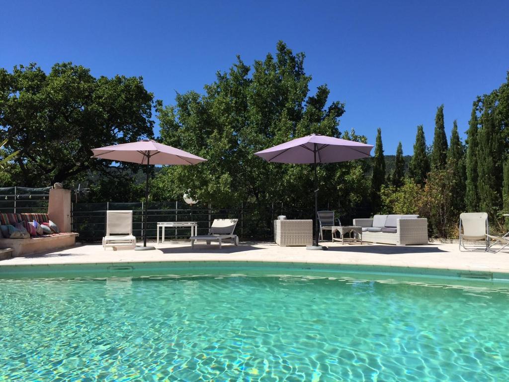 a swimming pool with chairs and umbrellas at Le Jas Du Colombier in Moustiers-Sainte-Marie