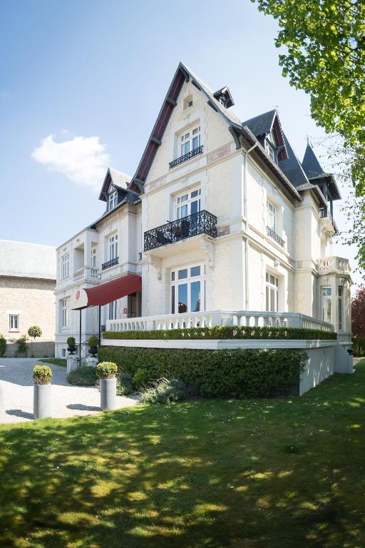 une grande maison blanche avec une pelouse devant dans l'établissement Villa 81, à Deauville