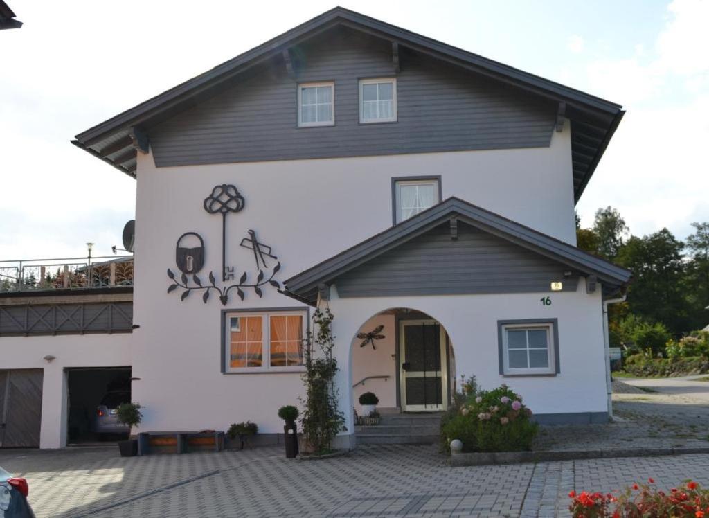 ein weißes Haus mit schwarzem Dach in der Unterkunft Erlebnispension Zum Wanderer Sepp in Arnbruck