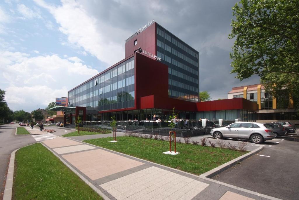 un grande edificio rosso con macchine parcheggiate di fronte di Hotel Park Doboj a Doboj