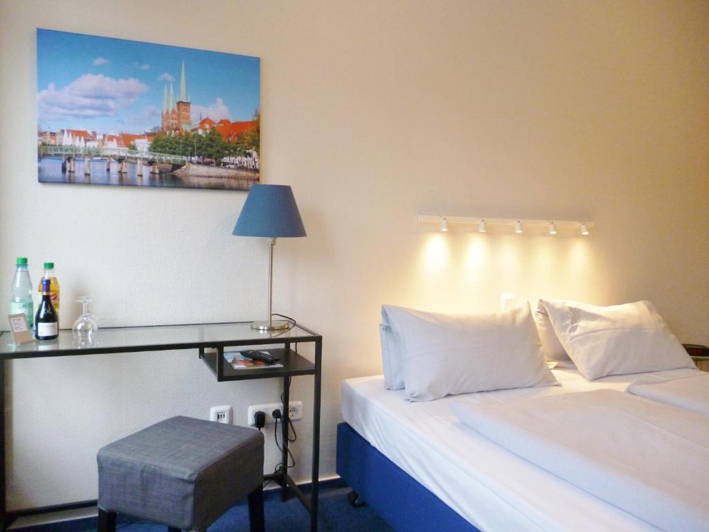 een slaapkamer met een bed en een bureau met een foto aan de muur bij Hotel Am Mühlenteich in Lübeck