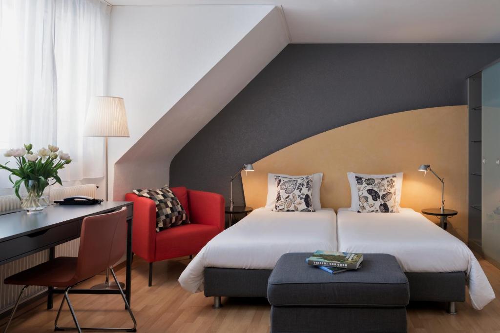 a bedroom with a bed and a desk and a chair at Hotel La Pergola in Bern