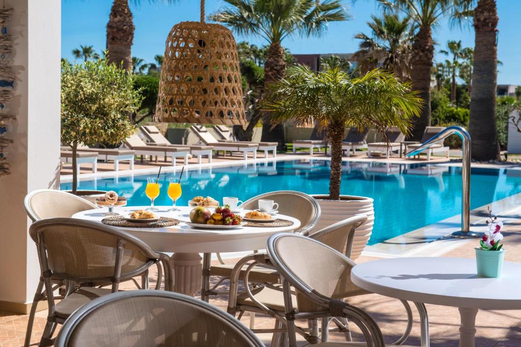 a table with food and drinks next to a swimming pool at Ammos Boutique Apartments & Suites in Malia