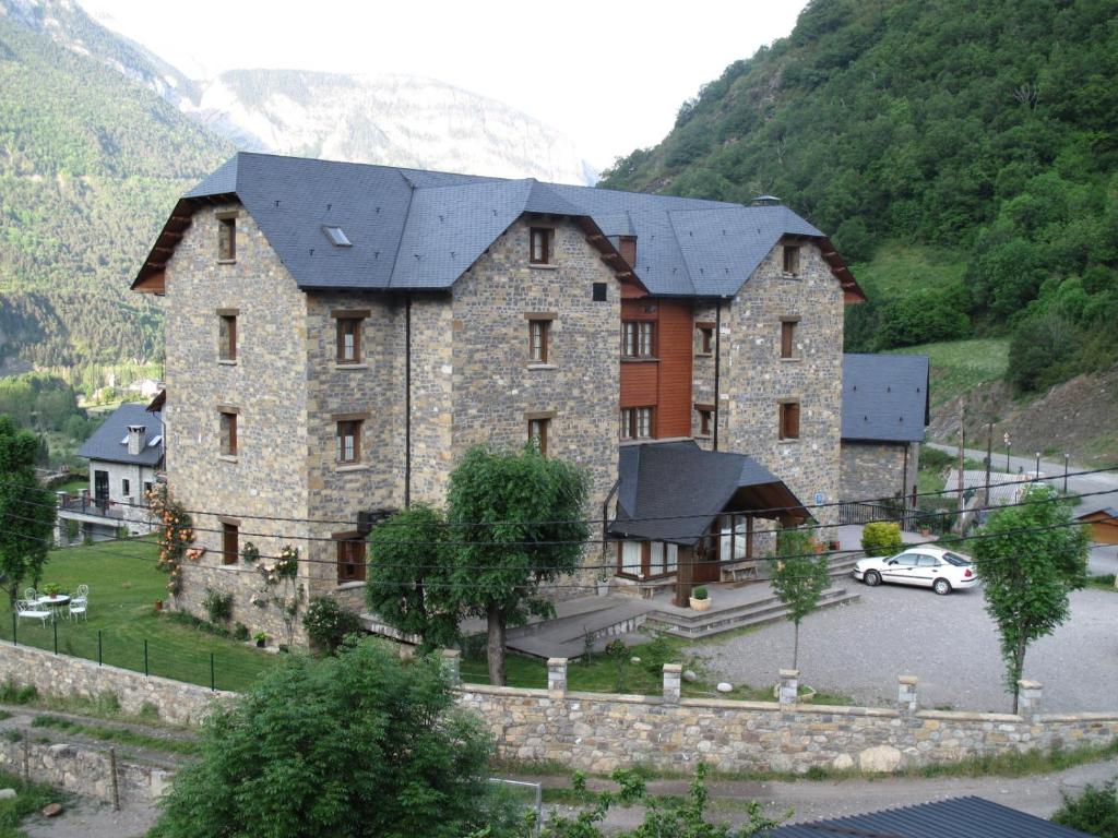 un grand bâtiment en pierre avec une voiture garée dans un parking dans l'établissement Hotel Casa Anita, à San Juan de Plan