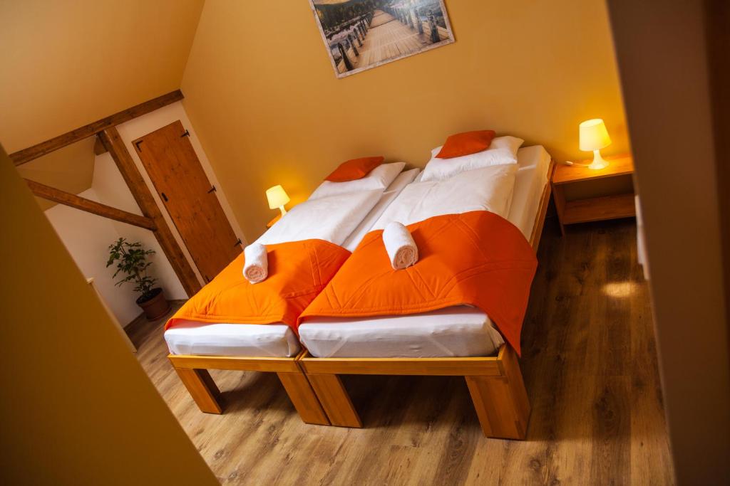 1 dormitorio con 1 cama con sábanas de color naranja y blanco en Lótuszvirág Vendégház, en Szekszárd