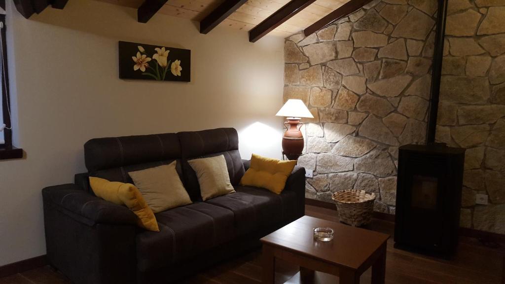 sala de estar con sofá y pared de piedra en El Cordel de Gredos, en Navarredonda de Gredos
