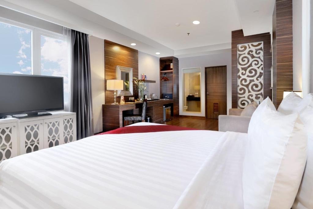 een slaapkamer met een groot wit bed en een televisie bij Pranaya Boutique Hotel in Serpong