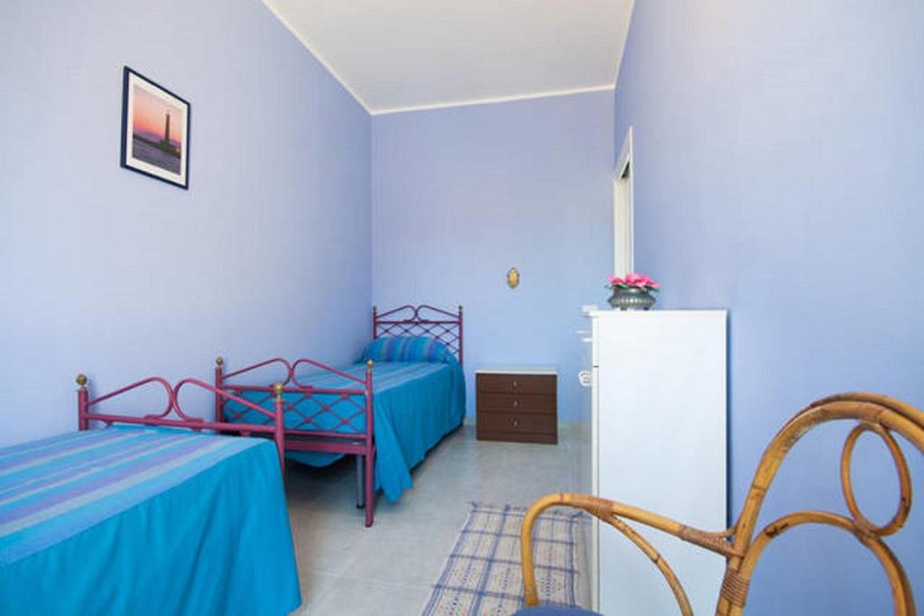 niebieski pokój z 2 łóżkami i lodówką w obiekcie Seaside Apartment w mieście San Vito lo Capo