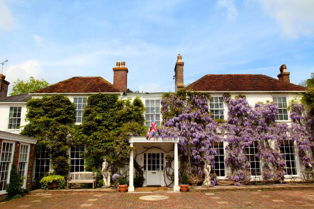 una casa con flores púrpuras en la parte delantera en Powdermills Country House Hotel en Battle