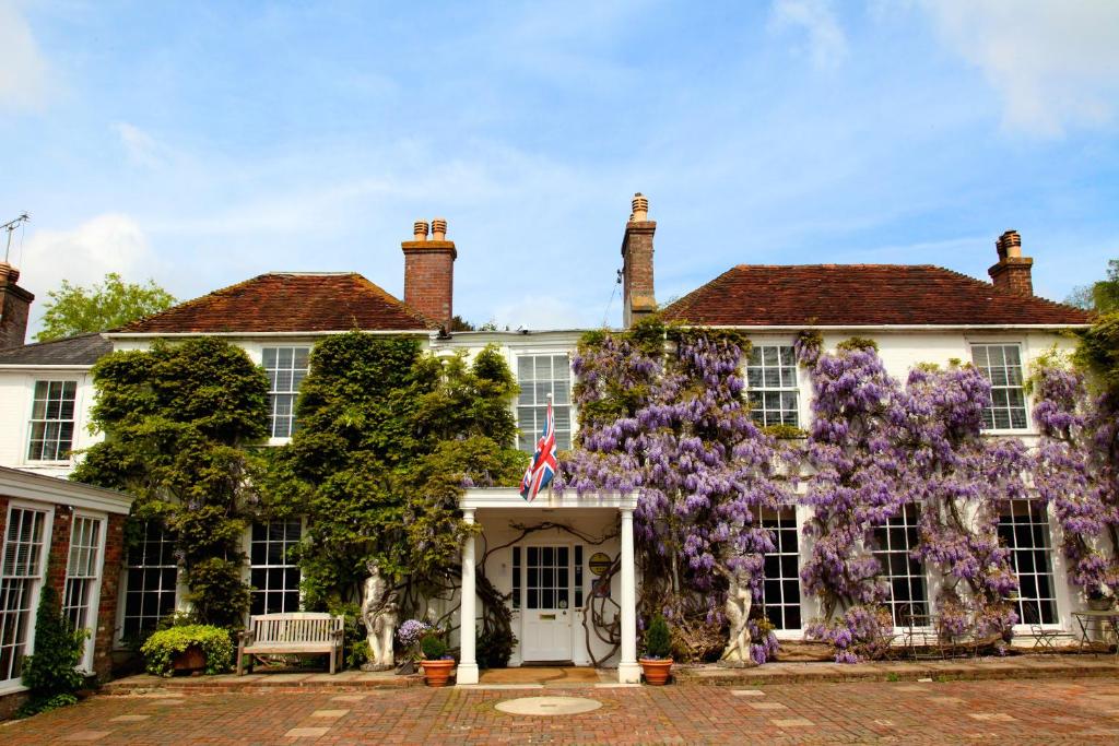 una casa con flores púrpuras en la parte delantera en Powdermills Country House Hotel, en Battle