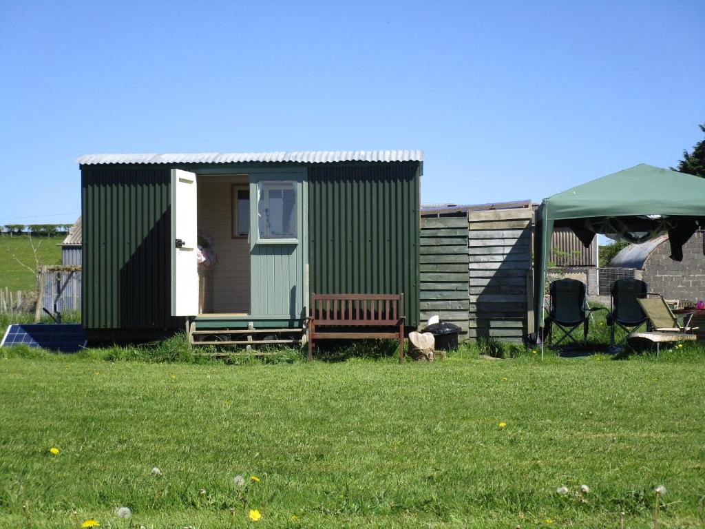 a green tiny house with a tent and two chairs at Bryn Parc in Llandysul