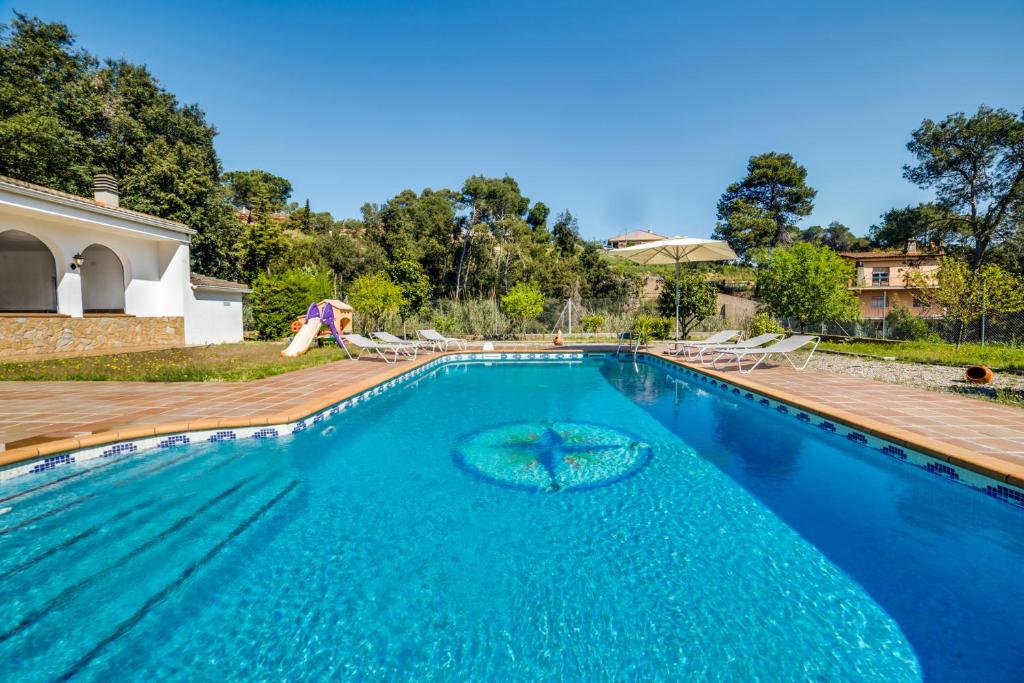 uma piscina com água azul e um deque de madeira em Vivalidays Casa Genis em Palafolls