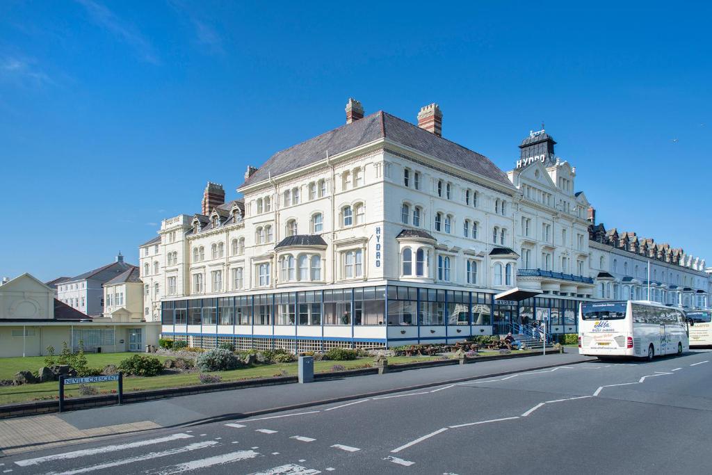 a white bus parked in front of a white building at Hydro Hotel in Llandudno