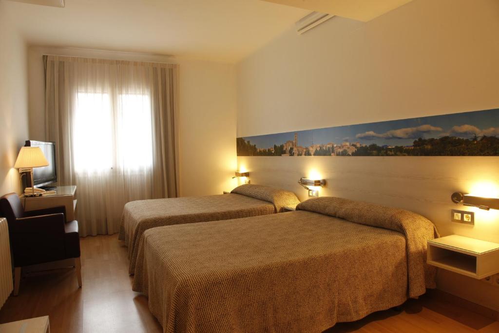 a hotel room with two beds and a painting on the wall at Hotel Canet in Castelló d'Empúries