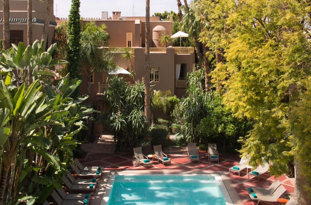 - une vue sur la piscine bordée de chaises et d'arbres dans l'établissement Les Jardins De La Médina, à Marrakech
