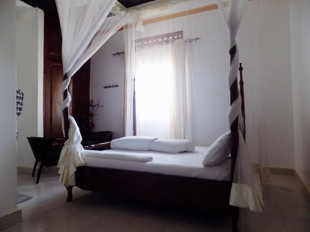 a bedroom with a canopy bed with a window at Star Royal Motel Kitebi Kampala in Kampala