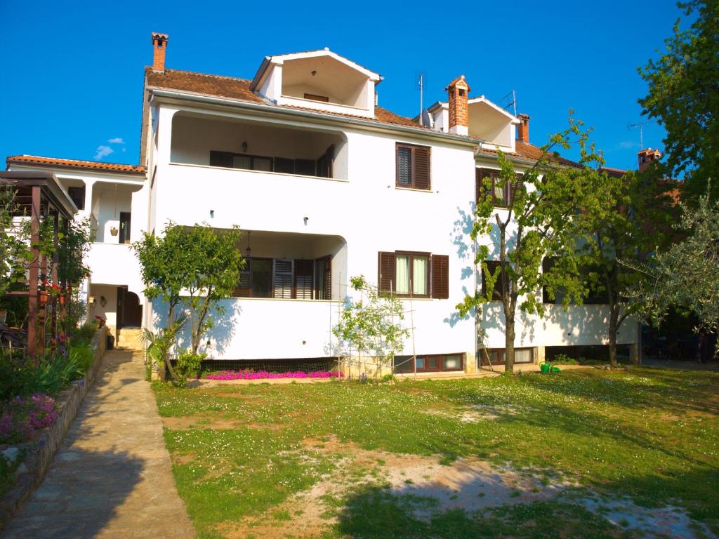 a white house with a yard in front of it at Nada Apartments in Poreč