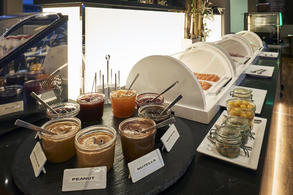 a table with jars of honey and other food items at LÉGÈRE HOTEL Luxembourg in Luxembourg